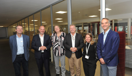 Henning Ueck, Niclas Herbst samt Delegation, Marianne Boskamp und Henrik Hesse vor der Produktionslinie in Hauptgebäude in Hohenlockstedt stehend.